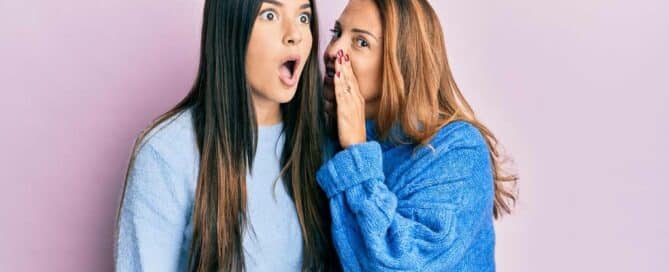 A woman whispering in to the other woman's ear